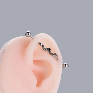 Detail of silver snake-shaped industrial barbell earring on silicone ear model