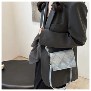 Close-up of a light blue quilted crossbody bag with denim texture and metal chain strap