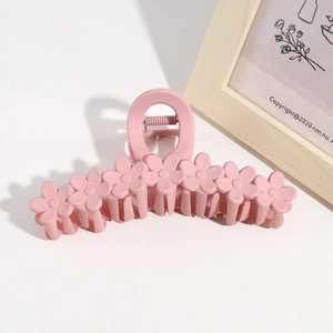 Detail of pink 13cm flower hair claw clip with matte finish on minimalist white background