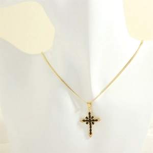 Close-up of cross pendant featuring black marquise stones and 18K gold snake chain