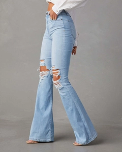 Vue détaillée du jean évasé taille haute bleu clair avec déchirures stylées au genou