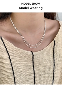 Close-up of double-layered 925 silver necklace on model wearing striped knitwear