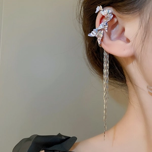 Close-up of butterfly ear cuff with long metallic tassels on model for sweet-cool style