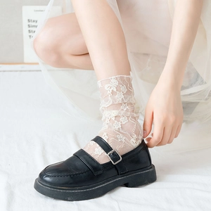 Detail of white floral lace socks paired with black Mary Jane shoes and a tulle dress