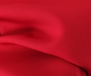 Close-up of red ruffled cake dress fabric showing fine plain weave texture and drapery