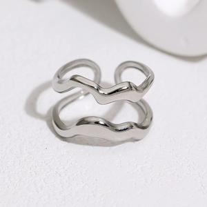 Detailed view of silver double-layered wave ring on white textured surface