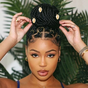 Detailed close-up of golden hair rings and seashell charms woven into a braided hairstyle