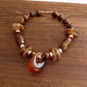 Detail view of amber beads and teardrop pendant on a vintage style necklace chain
