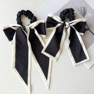 Detail of black and white ribbon bow hair ties with satin texture on minimalist background