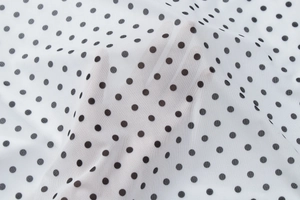 Detail of white mesh fabric with black polka dots showing semi-transparent texture