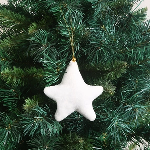 Close-up of a white plush star ornament with a gold cord on a green Christmas tree