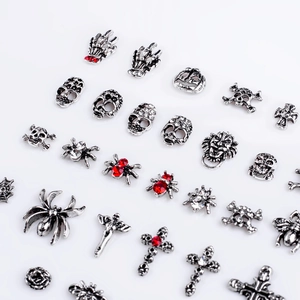 Close-up of gothic silver nail charms including skulls, spiders and crosses with rhinestones