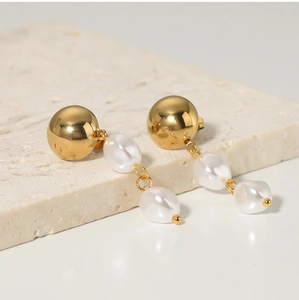 Detail of golden stainless steel stud earrings with elegant pearl tassel charms