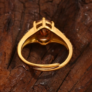 Detail of adjustable 18K gold plated ring with amber oval zircon on rustic wood surface