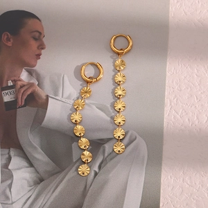 Close-up of golden long tassel earrings with sunburst disks on a fashion magazine