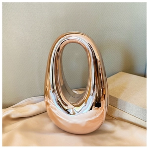 Detailed close-up of the smooth rose gold metal clasp on the oval acrylic clutch bag