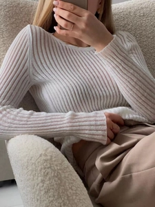 Detail of sheer cream long sleeve knit top featuring a delicate vertical ribbed texture