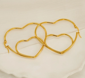 Detail shot of nested gold heart hoop earrings with layered geometric design on tray