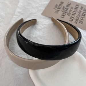 Minimalist wide PU leather headbands in black and beige displayed on a white tray