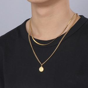 Detailed close-up of a double-layered gold coin pendant necklace on a black shirt