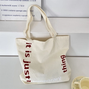 Gros plan du sac fourre-tout en toile beige avec texte imprimé dans un décor épuré