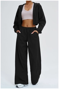 Close-up of black high-waisted wide-leg sports pants paired with white sneakers