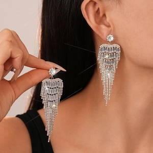 Détail macro de boucles d'oreilles pampilles argentées avec zircons sur un modèle