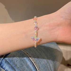 Primer plano de pulsera de cuentas de corazón y mariposa con degradado macaron en la muñeca