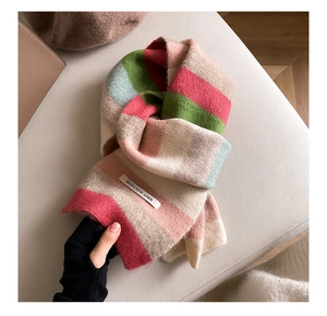 Close-up of rainbow mohair scarf with pink, green, and beige stripes and a sewn-on label