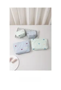 Detail of striped fabric makeup bags with bow embroidery and secure zipper closure
