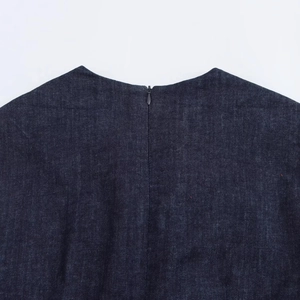 Gros plan détaillé sur la fermeture éclair invisible du dos de la robe en jean bleu
