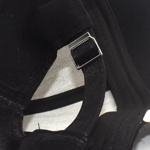 Macro shot of adjustable metal slider and black strap on back of baseball cap