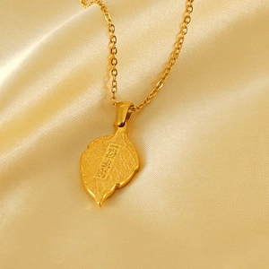 Macro detail of leaf pendant with fortune engraving on luxury gold satin fabric