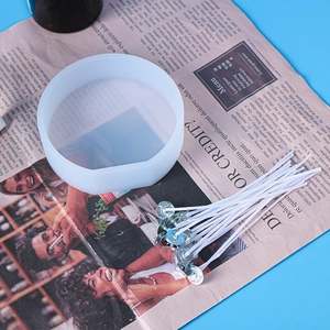 DIY candle kit with a round silicone mold and white wicks with metal bases on vintage paper