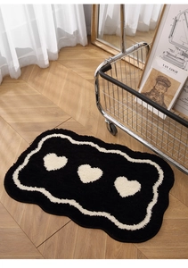 Detail of plush black and white wavy rug with heart patterns on a wooden floor
