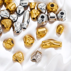 Detailed view of baroque gold and silver stainless steel loose beads on white silk