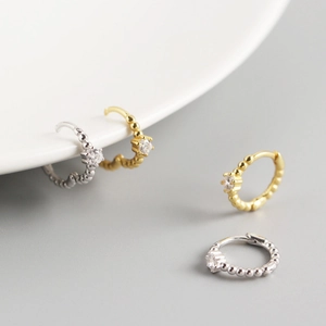Detail of round hoop earrings in gold and silver finish with tiny beads and inset zircons