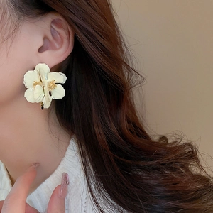 Close-up of vintage flower petal earrings with white enamel and golden center on model