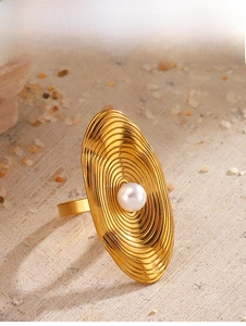 Detail view of oval gold ring featuring concentric water ripple texture and pearl inlay