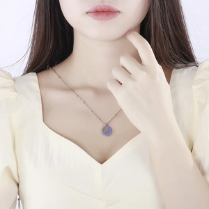 Close-up of a minimalist rose gold titanium necklace with a blue zodiac pendant
