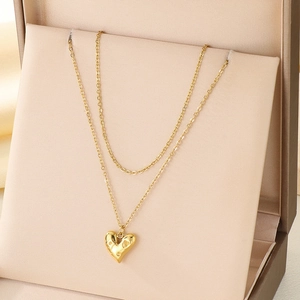 Détail d'un collier doré à double couche avec pendentif cœur dans son écrin beige