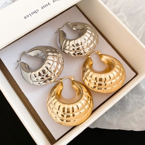 Close-up of gold and silver C-shaped earrings with quilted texture in a white gift box