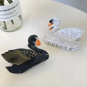 Close-up of black and white swan-shaped acetate hair claws with shell texture detail