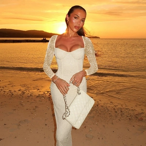 Elegantes weißes langärmliges Spitzenkleid mit quadratischem Ausschnitt am Strand
