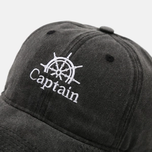 Macro view of white Captain embroidery and fabric texture on washed dark grey cotton cap