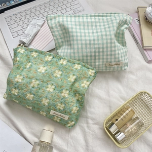 Detailed top view of plaid and floral cosmetic pouches on a white fabric surface