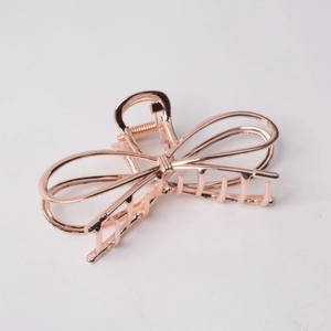 Close-up of elegant rose gold metal bow hair claw clip with cutout design and spring