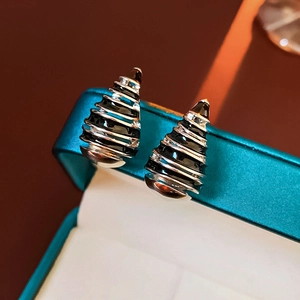 Close-up of vintage silver earrings with black enamel stripes on a blue jewelry box