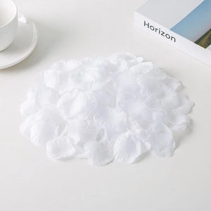 Close-up of white non-woven fabric rose petals scattered on a desk with a coffee cup