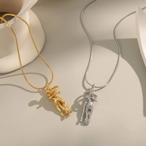 Artistic gold and silver hug pendant necklaces on minimalist ceramic decor